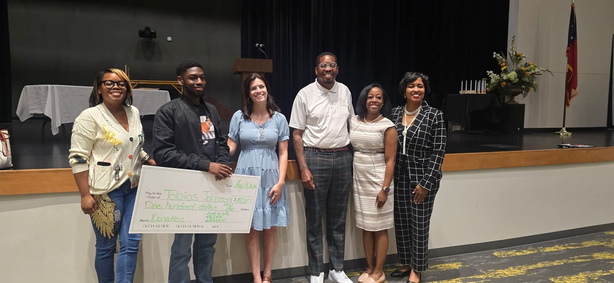 NAFYEAVP presenting a scholarship donation to Tobias Johnson at a community event